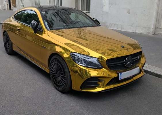 golden mercedes polished to a high shine parked on a side road in the middle of a city