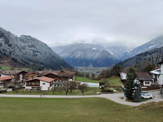 large mountain seen from the valley with a few huts and epic fog in the background